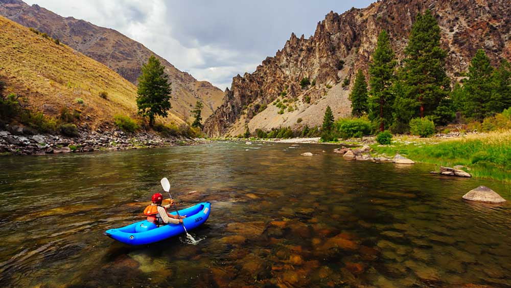 An inflatable kayak floats along a calm stretch while whitewater rafting on the Middle Fork Salmon River in Idaho with ARTA river trips