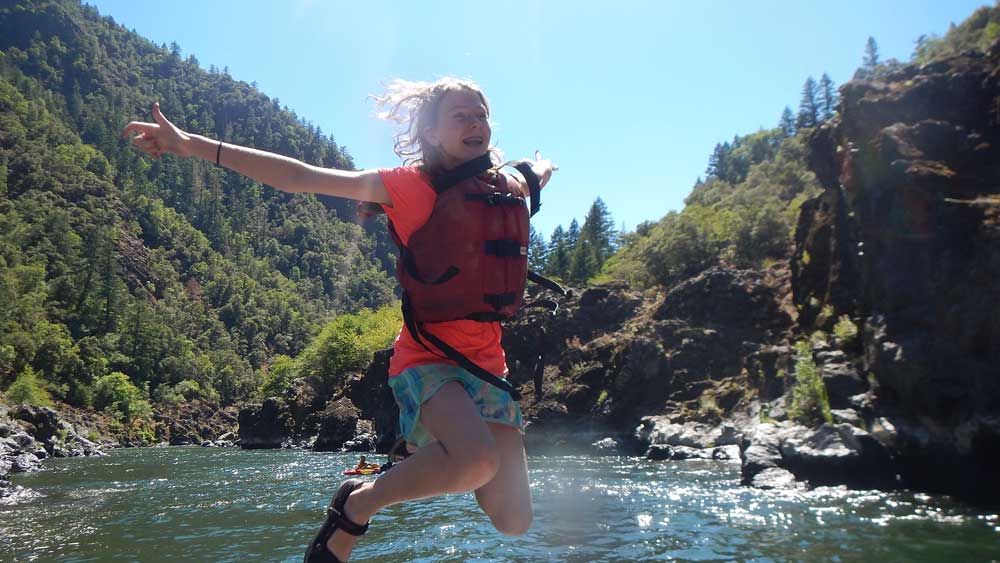 Jumping into the river while whitewater rafting on the Rogue River in Oregon with ARTA river trips