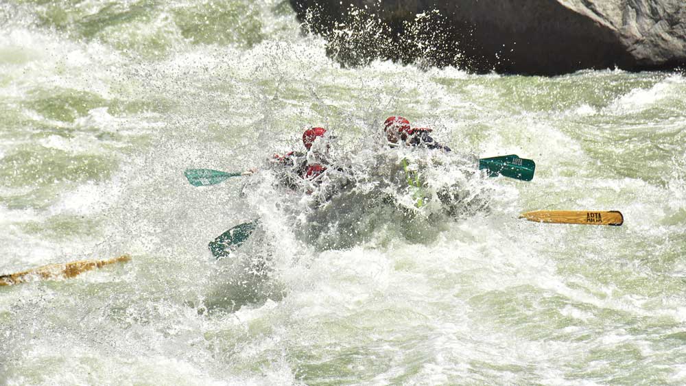 an oar-paddle raft gets wet in Split Rock rapid while whitewater rafting on the Merced River in California with ARTA river trips