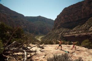Two people do yoga overlooking a river