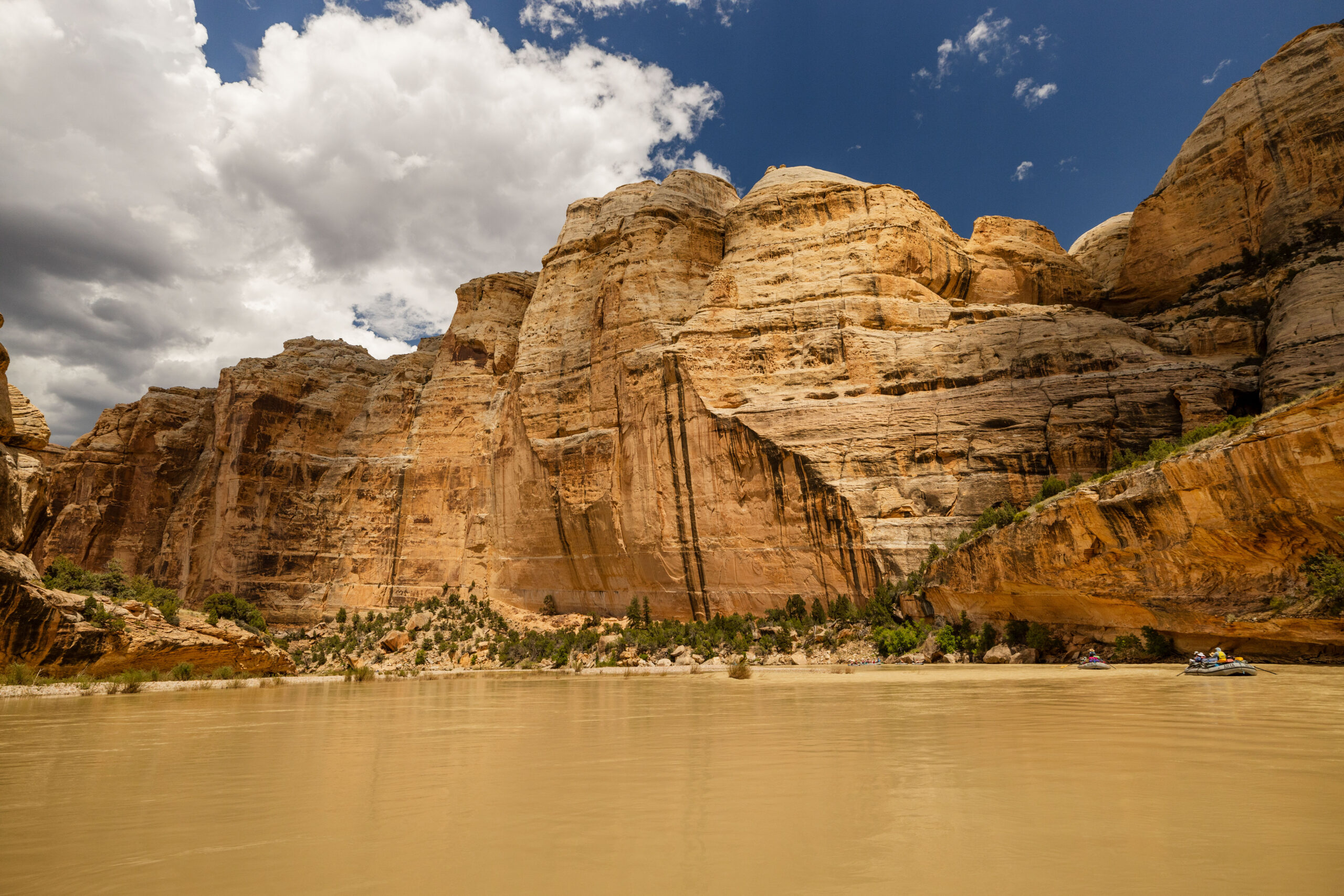 A scenic view of the brown yampa river flowing against a rock wall