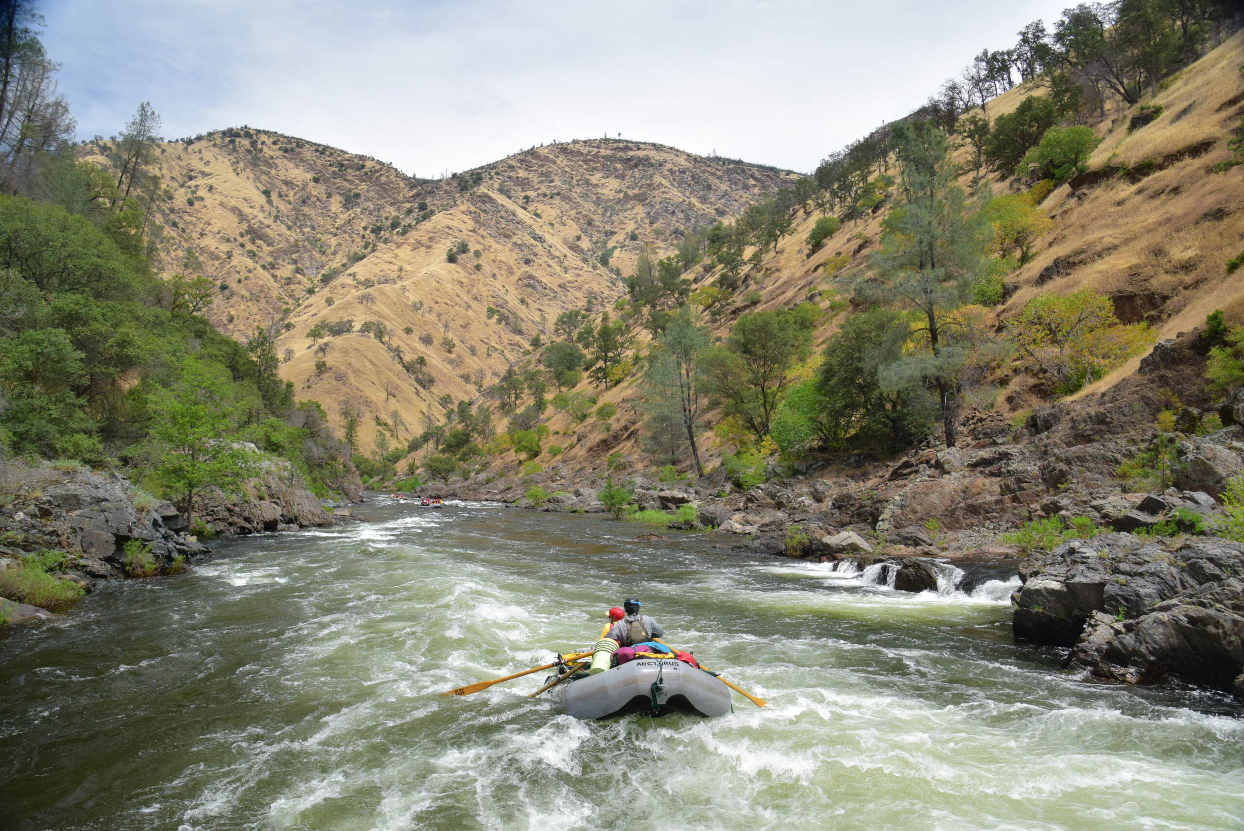 A river guide paddles a raft down the tuolumne river