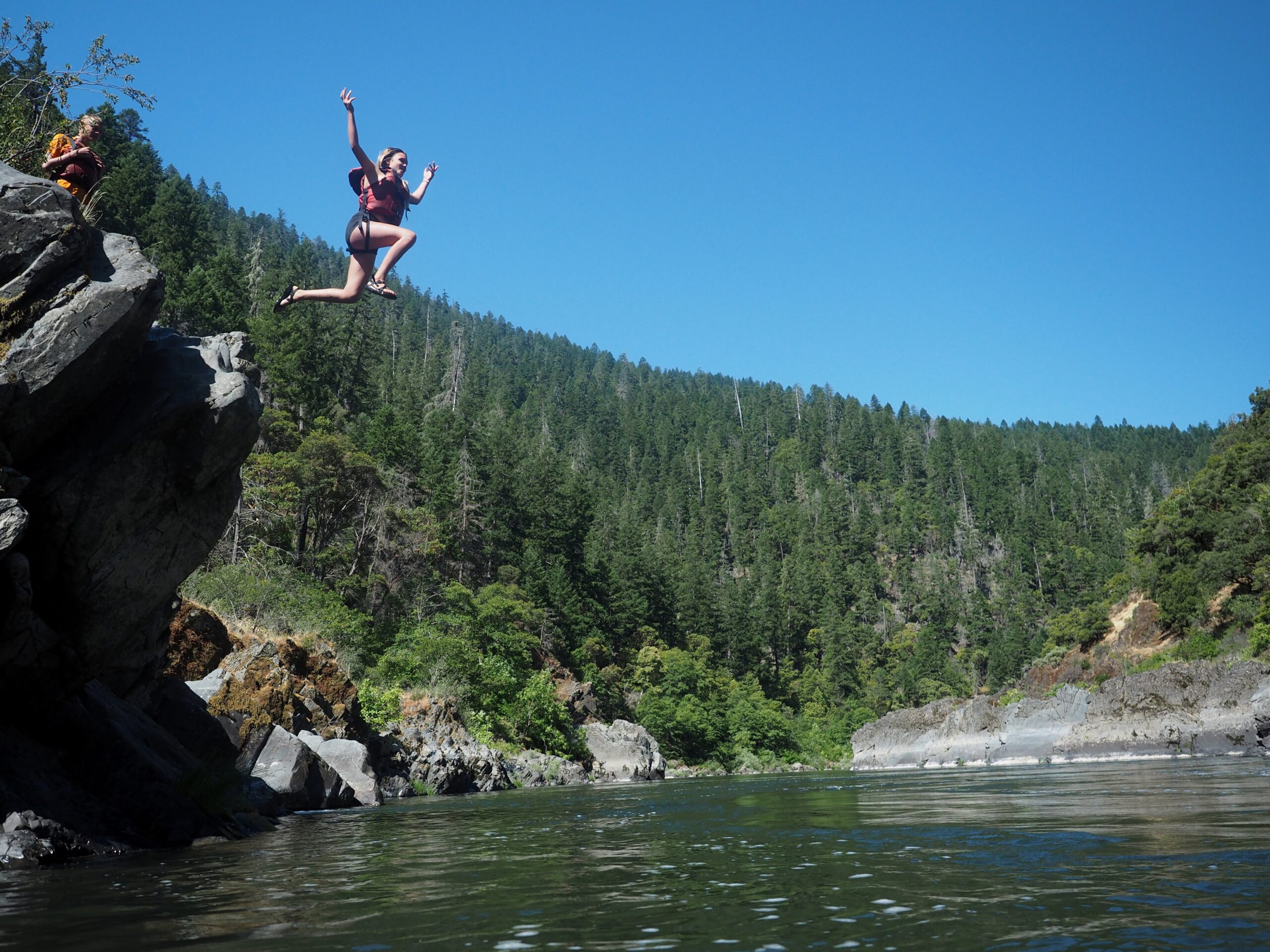A person jumps off a rock on the rogue river