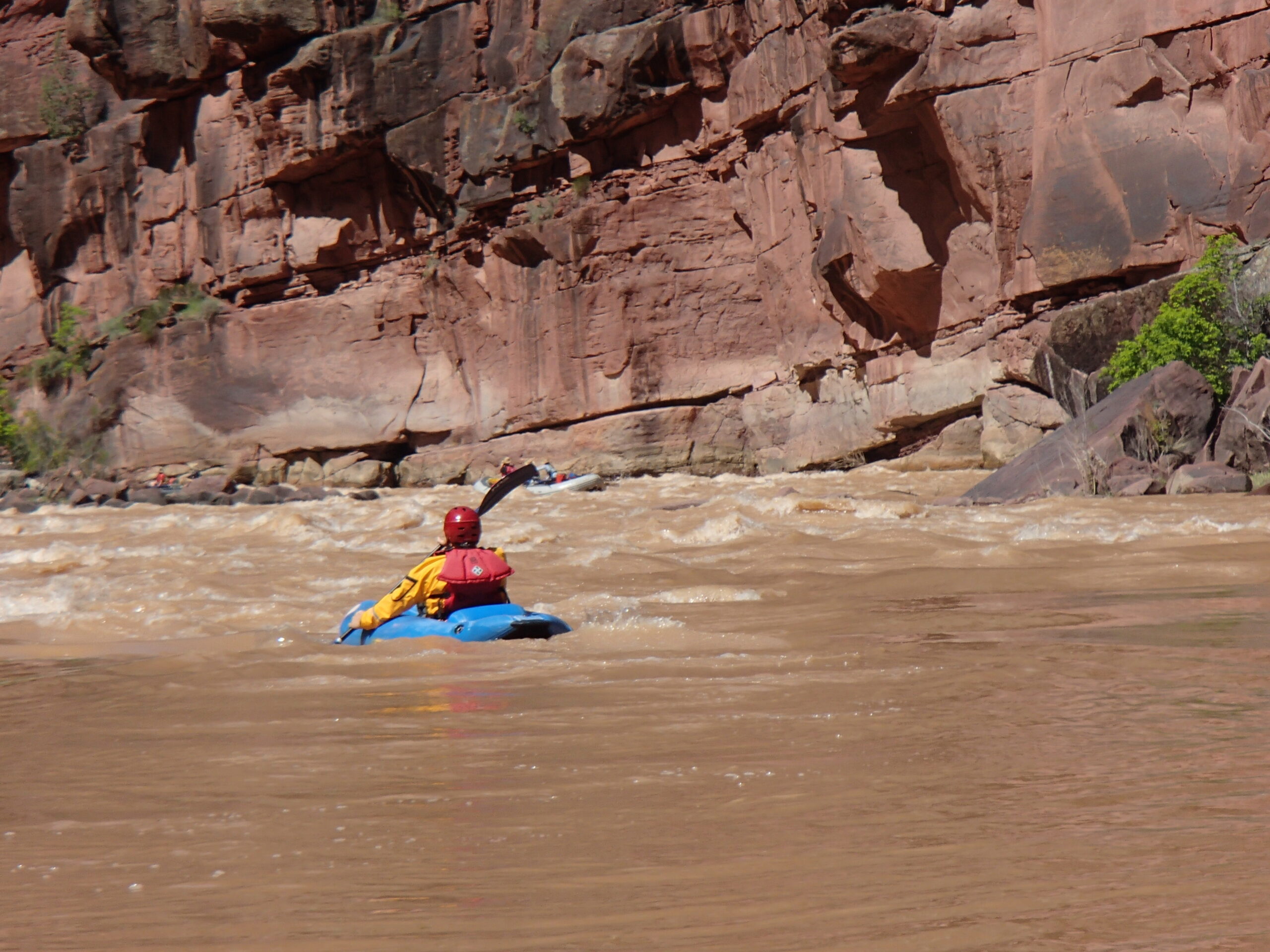 A person in a kayak paddles through the brown waters of the green river