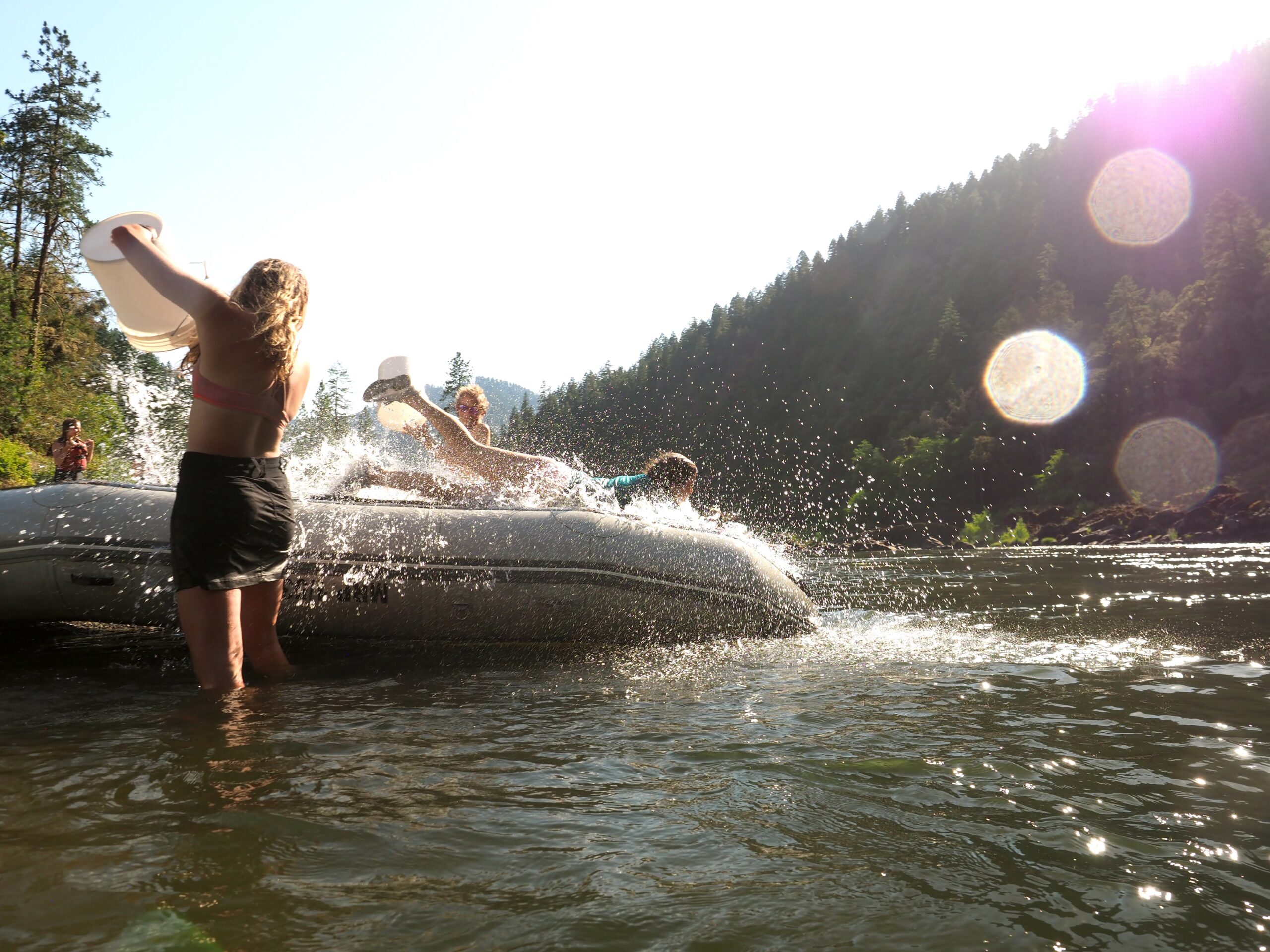 A person sliding on the backside of a raft into the river