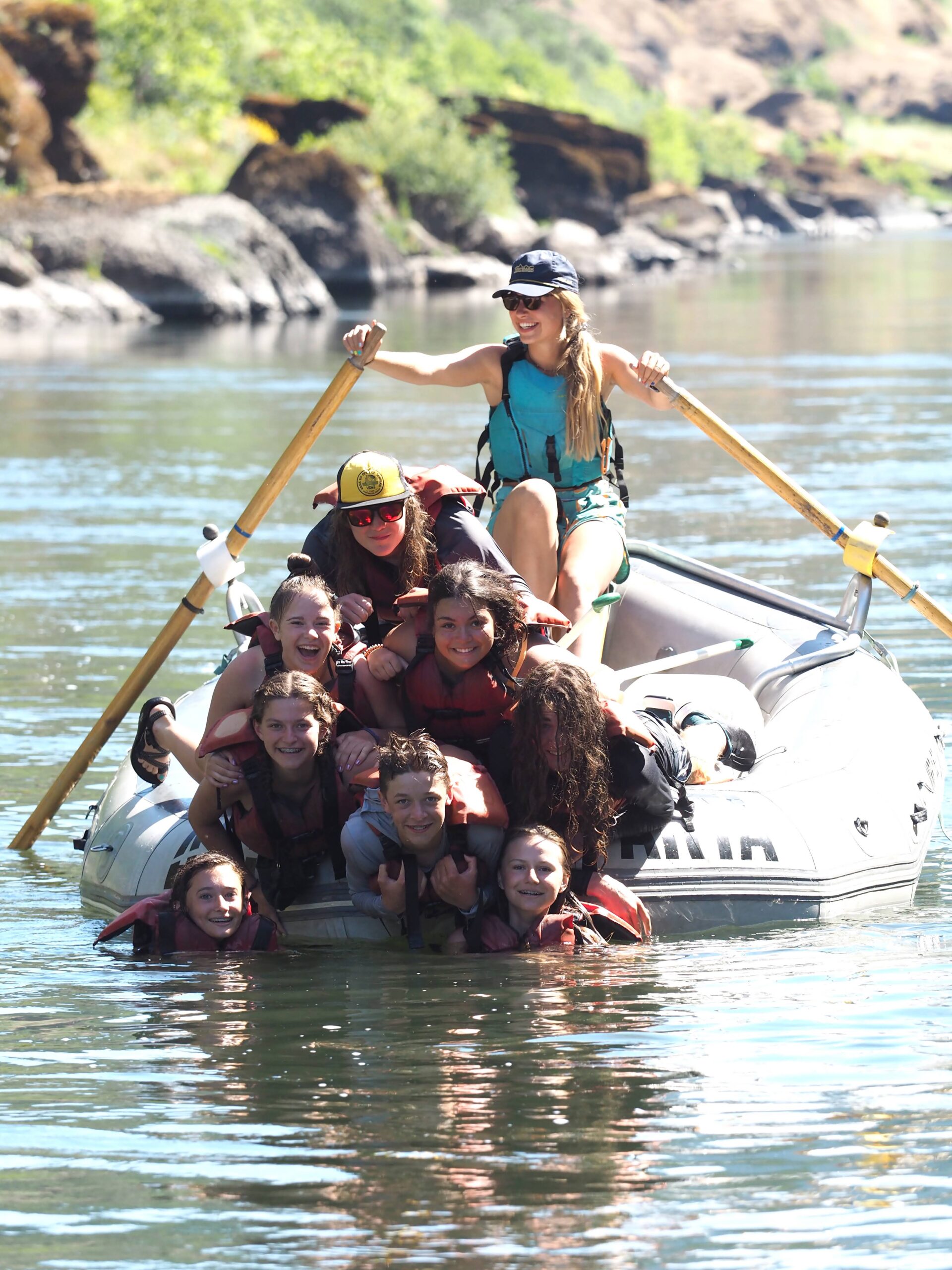 A group of people on a grey raft on the rogue river
