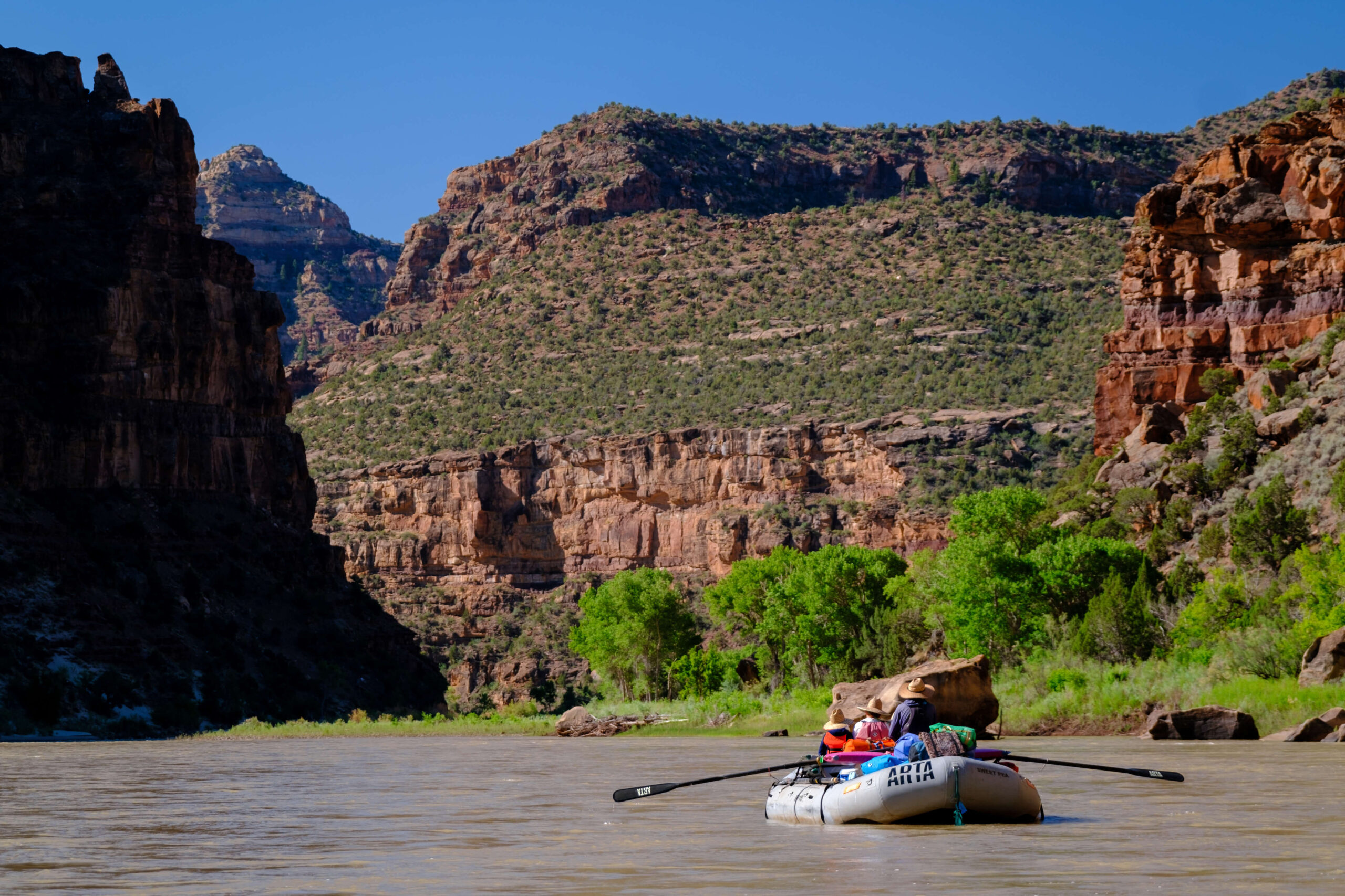 A raft filled with camping gear floats down the green river