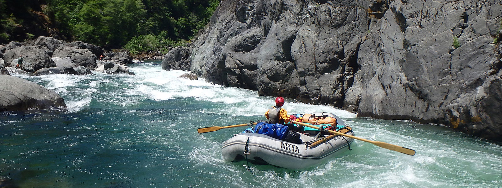 A raft with one person prepares to paddle through rapids