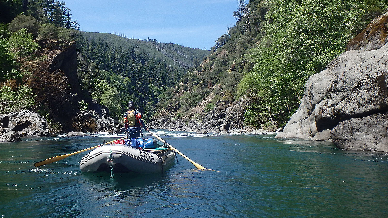 A river guide stands up in his raft to find his next rafting line