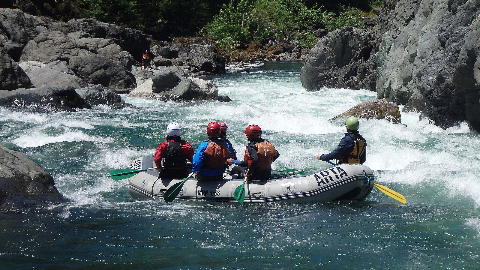 A raft willed with people prepares to paddle through rapids